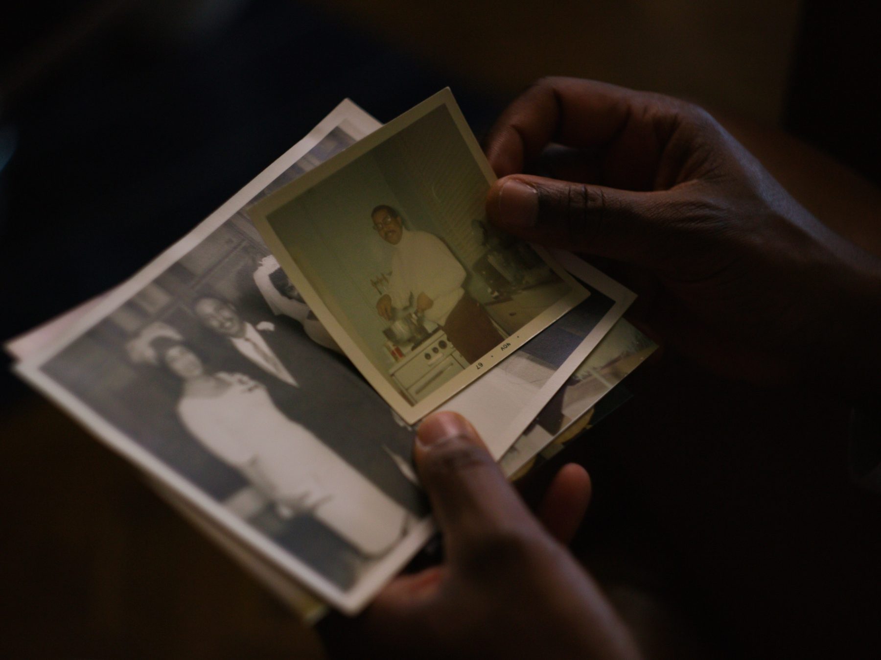 Hands holding a stack of vintage family photographs