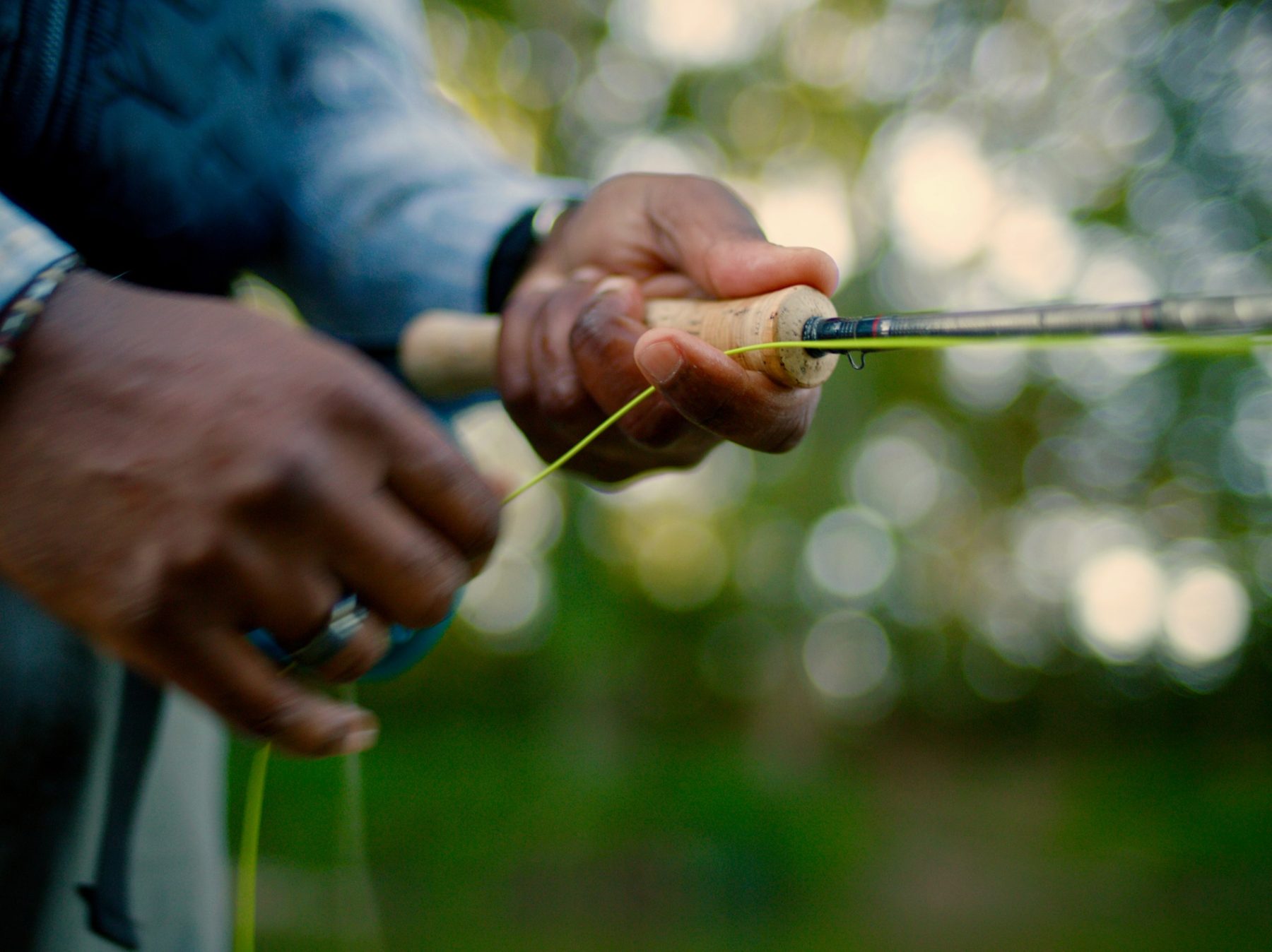Close-up of Al's hands stripping fly line from a cork-handled rod